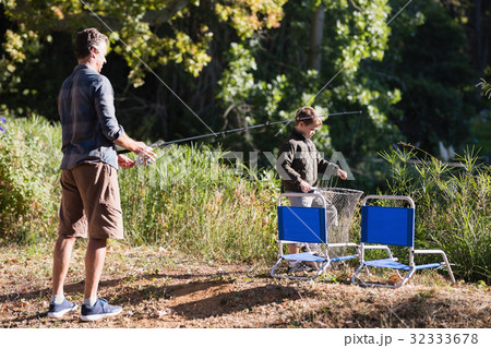 Father and son holding fishing equipment in forest Father and son holding fishing equipment in forest 32333678