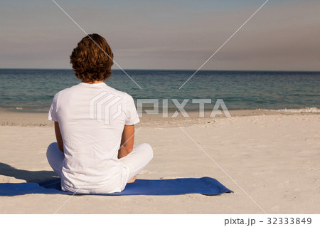Rear view of man meditating at beach 32333849