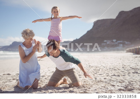 Happy girl kneeling on father back at beach Happy girl kneeling on father back at beach 32333858