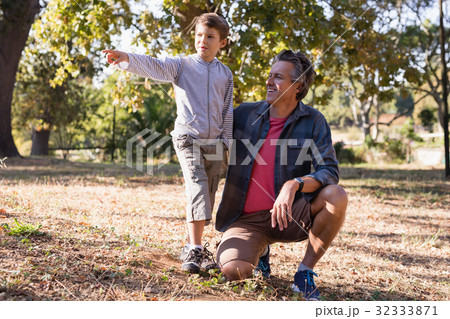 Happy man looking at boy pointing away in forest Happy man looking at boy pointing away in forest 32333871