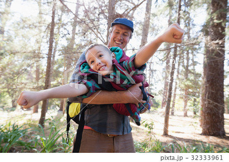 Playful father carrying son in forest Playful father carrying son in forest 32333961