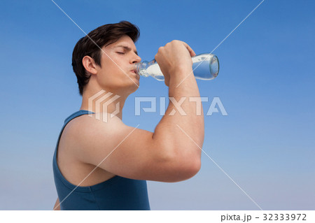 Man drinking water from bottle at beach 32333972