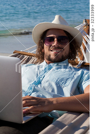Man using laptop while relaxing on hammock 32333999