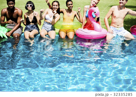 Diverse young adult sitting by swimming pool Diverse young adult sitting by swimming pool 32335285