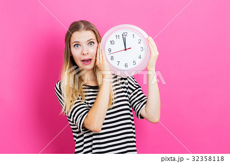 Woman holding clock showing nearly 12 32358118