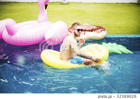 Caucasian tattooed man floating in the swimming pool by inflatable 32369026