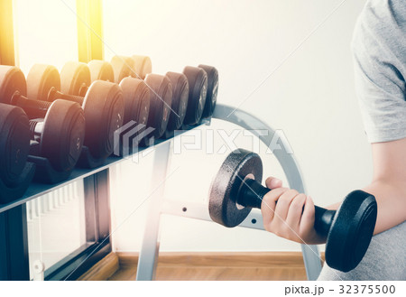 Hand of woman taking a dumbbell out of set 32375500