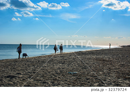 Silhouettes of people walking on a beach at sunset Silhouettes of people walking on a beach at sunset 32379724