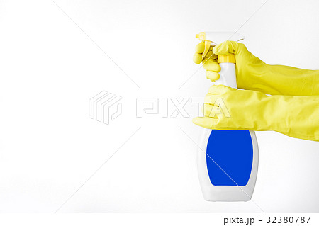 Hand in rubber yellow glove holds  spray bottle o 32380787