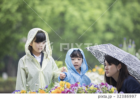 雨合羽を着て花を見る小学生の写真素材