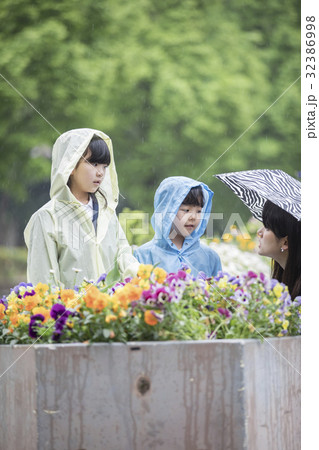 雨合羽を着て花を見る小学生の写真素材