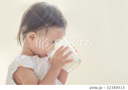 Cute asian toddler girl drinking milk from glass. 32389513