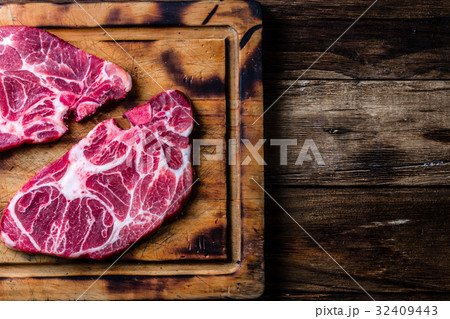 Raw marbled beef steaks on wooden cutting board Raw marbled beef steaks on wooden cutting board 32409443