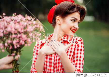 Glamour pinup girl takes gift a bouquet of flowers 32411682