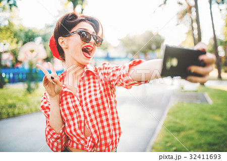 Pinup sexy lady makes selfie on camera in park 32411693