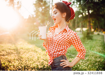 Pin up girl holds cardboard cup with a straw 32411698