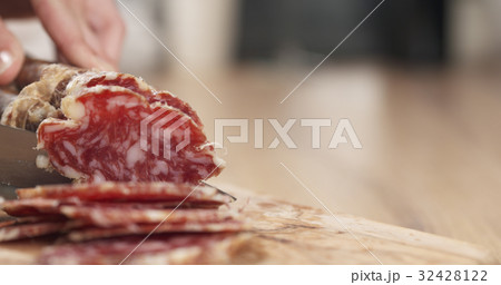 female teen hand slicing dried italian salami 32428122