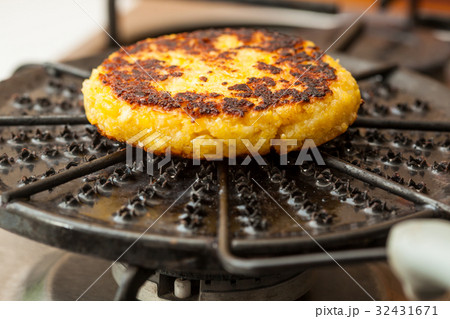 Arepa (Corn bread) being roasted on a round grill Arepa (Corn bread) being roasted on a round grill 32431671