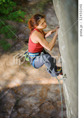 Beautiful woman climber climbing steep rock with rope Beautiful woman climber climbing steep rock with rope 32450340