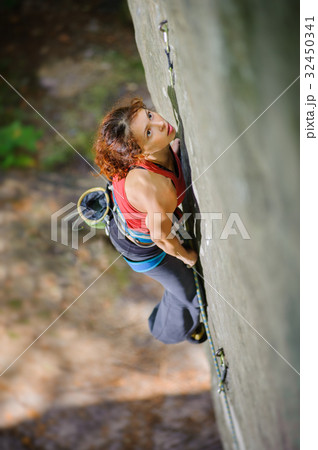 Beautiful woman climber climbing steep rock with rope 32450341
