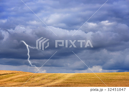 Dark storm clouds and lightning above autumn field 32451047