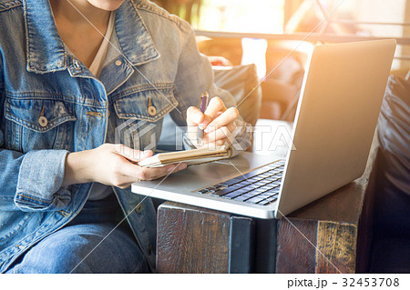 woman's hand using laptop and writing in notepad. woman's hand using laptop and writing in notepad. 32453708
