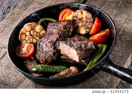 Juicy steak with vegetable garnish on an old Juicy steak with vegetable garnish on an old 32454273