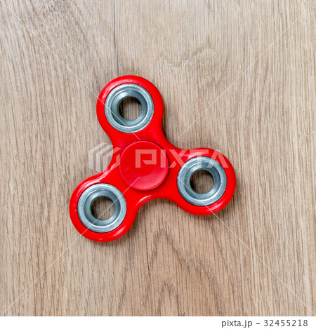 Fidget spinner. Red hand spinner on wooden Fidget spinner. Red hand spinner on wooden 32455218