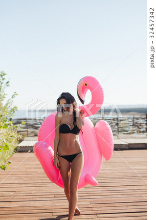 woman holding pink inflatable flamingo float 20s woman holding pink inflatable flamingo float 20s 32457342