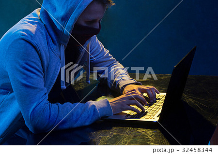 Hooded computer hacker stealing information with Hooded computer hacker stealing information with 32458344