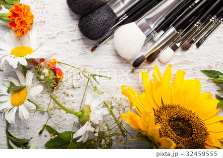 Make up brushes on a table next to wild flowers Make up brushes on a table next to wild flowers 32459555