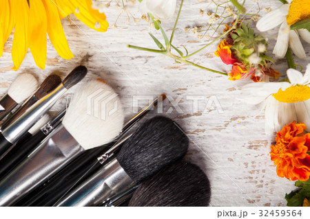 Make up brushes on a table next to wild flowers Make up brushes on a table next to wild flowers 32459564