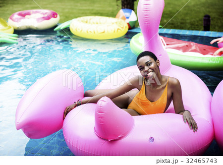 African descent girl floating on life ring in swimming pool African descent girl floating on life ring in swimming pool 32465743
