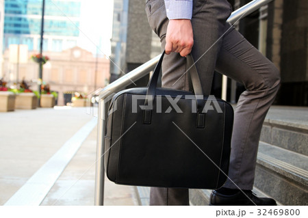 man walking and holding a briefcase in his hands 32469800