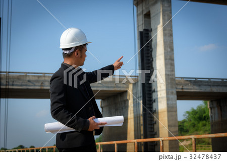 Asian young man engineers are holding a blueprint Asian young man engineers are holding a blueprint 32478437