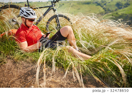 Cyclist in Red Jacket and Helmet Resting near Cyclist in Red Jacket and Helmet Resting near 32478650