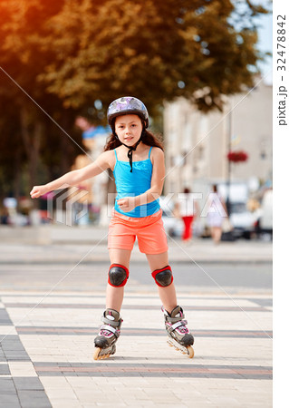 Cute little girl learning to roller skate in city 32478842