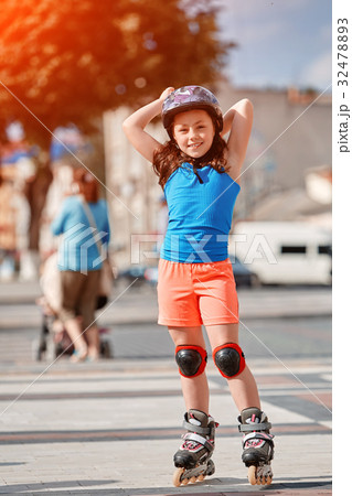 Cute little girl learning to roller skate in city 32478893