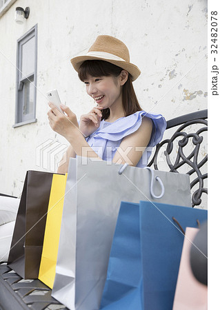 買い物の途中でベンチで休憩をする女性 買い物の途中でベンチで休憩をする女性 32482078