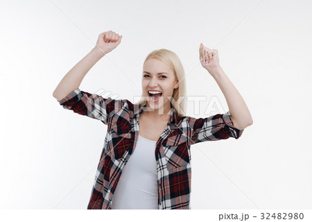 Pleased blonde raising her both arms up 32482980