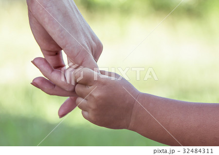 child and mother holding hand together with love  32484311