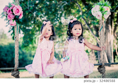 Children two cute little girls sitting on swing 32486588