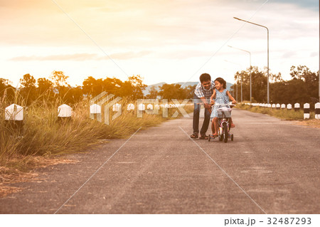 Asian girl having fun to ride bicycle with father 32487293