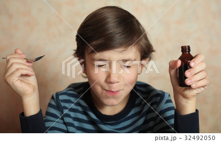 boy take sore medicine with spoon and bottle boy take sore medicine with spoon and bottle 32492050