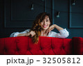 pretty brunette young woman posing behind red sofa 32505812