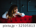 pretty brunette young woman posing behind red sofa 32505813