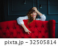 pretty brunette young woman posing behind red sofa 32505814