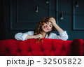 pretty brunette young woman posing behind red sofa 32505822