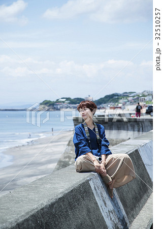 海 散歩 女性 撮影 カメラ 防波堤 海岸 旅行 観光 海辺の写真素材