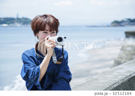 海 散歩 女性 撮影 カメラ 防波堤 海岸 旅行 観光 海辺の写真素材